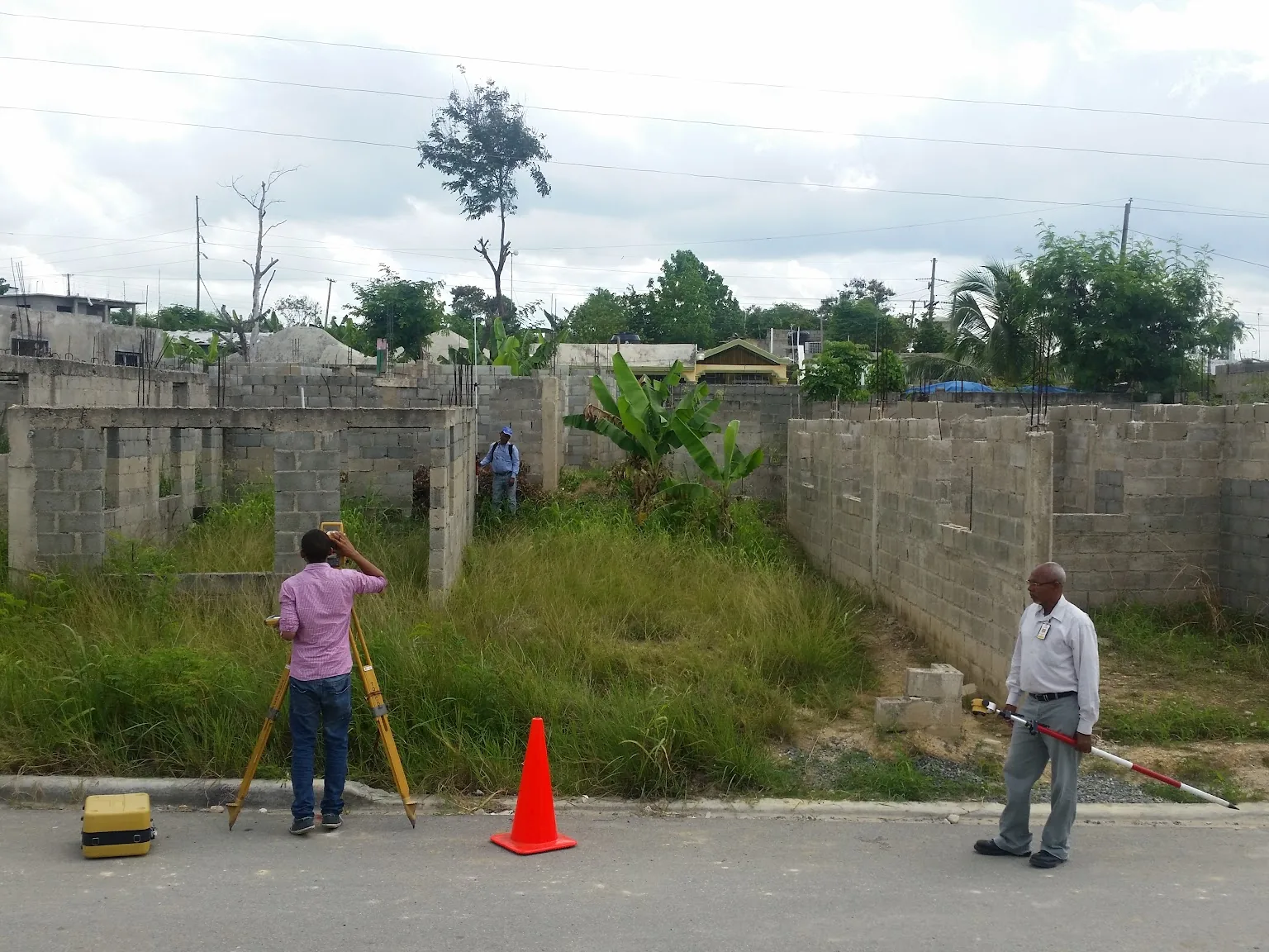 Equipo de agrimensura midiendo un solar con estación total y conos de seguridad